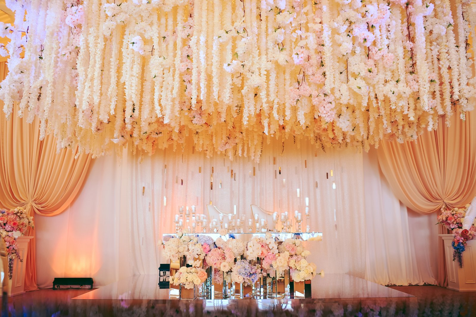 Wedding stage decorated with cascading flowers and candles